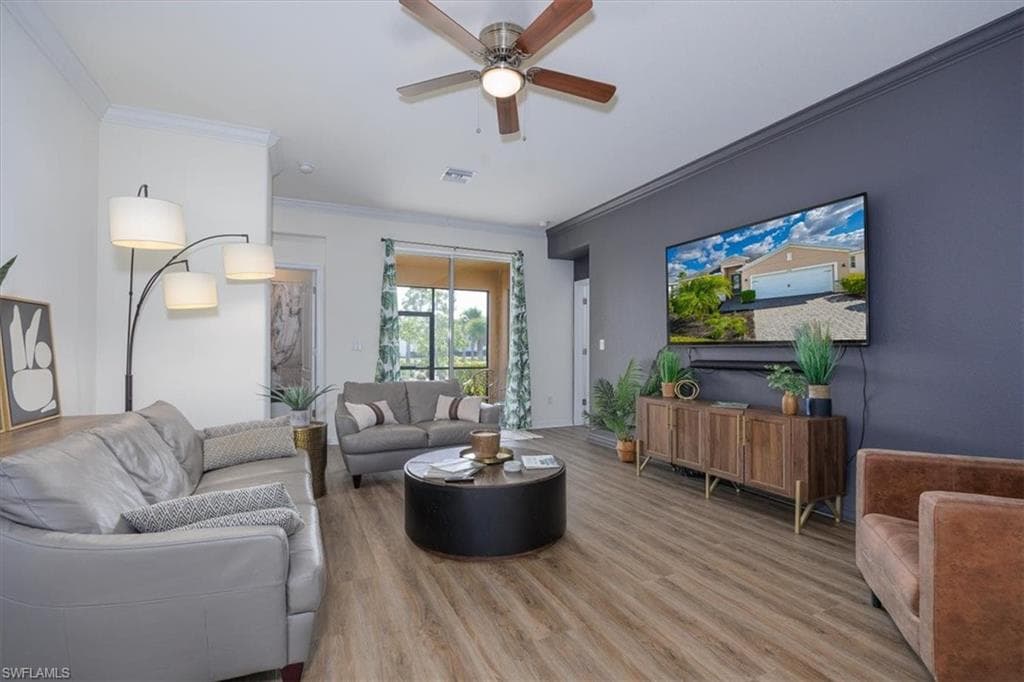 Living room with easy care flooring, ornamental molding, and ceiling fan
