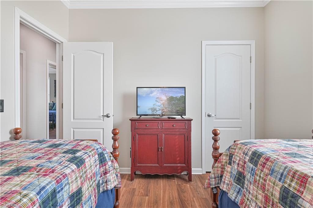 Bedroom with dark wood-style flooring and crown molding