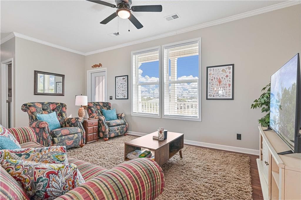 Living room featuring crown molding, wood finished floors, and a ceiling fan