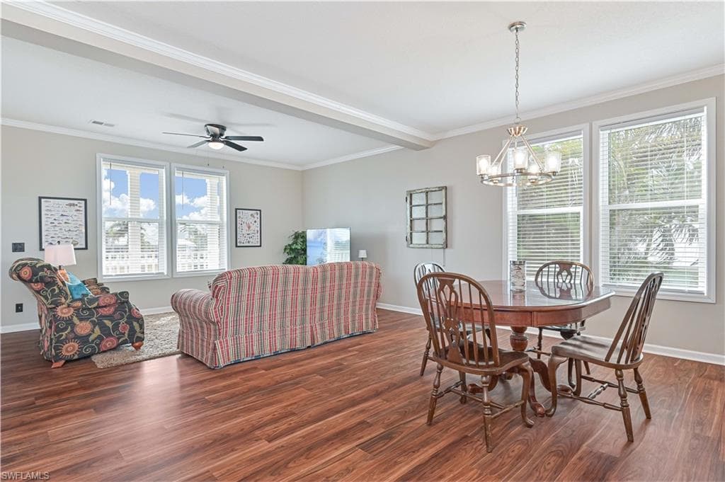 Dining room featuring crown molding, wood finished floors, ceiling fan, and a chandelier
