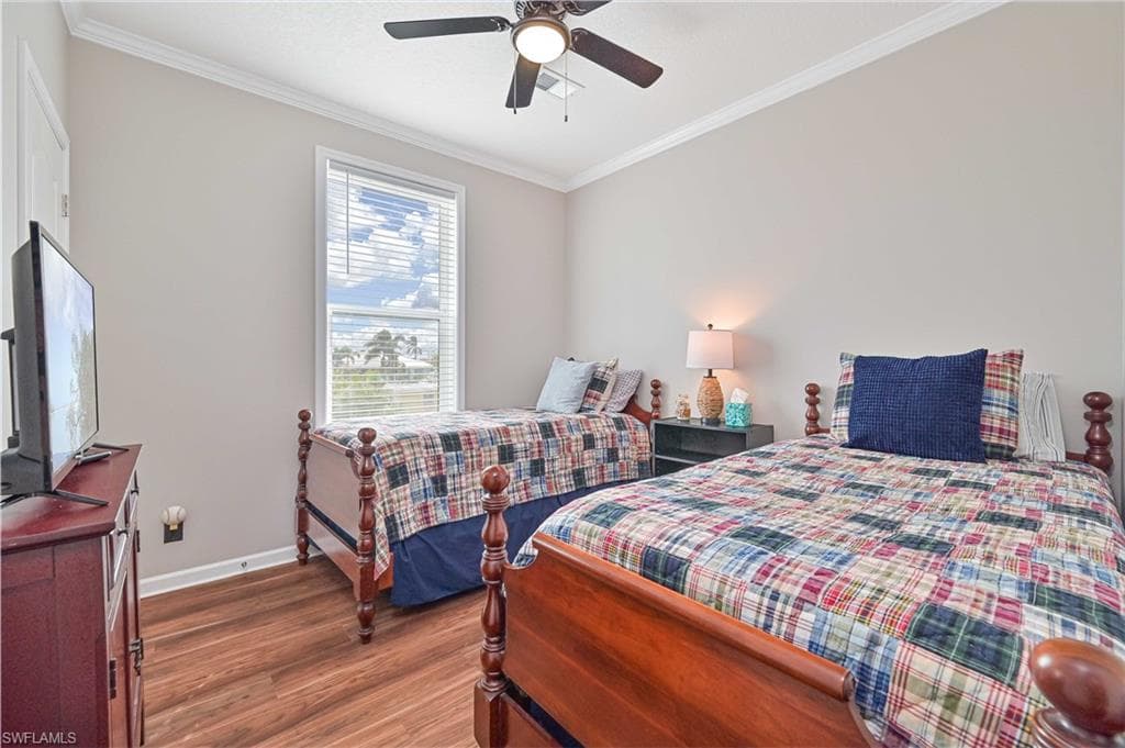 Bedroom with crown molding, wood finished floors, and a ceiling fan