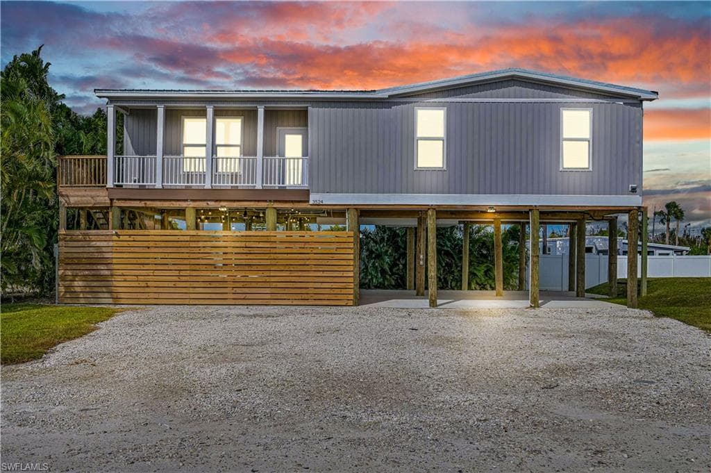 Raised beach house featuring driveway and a carport