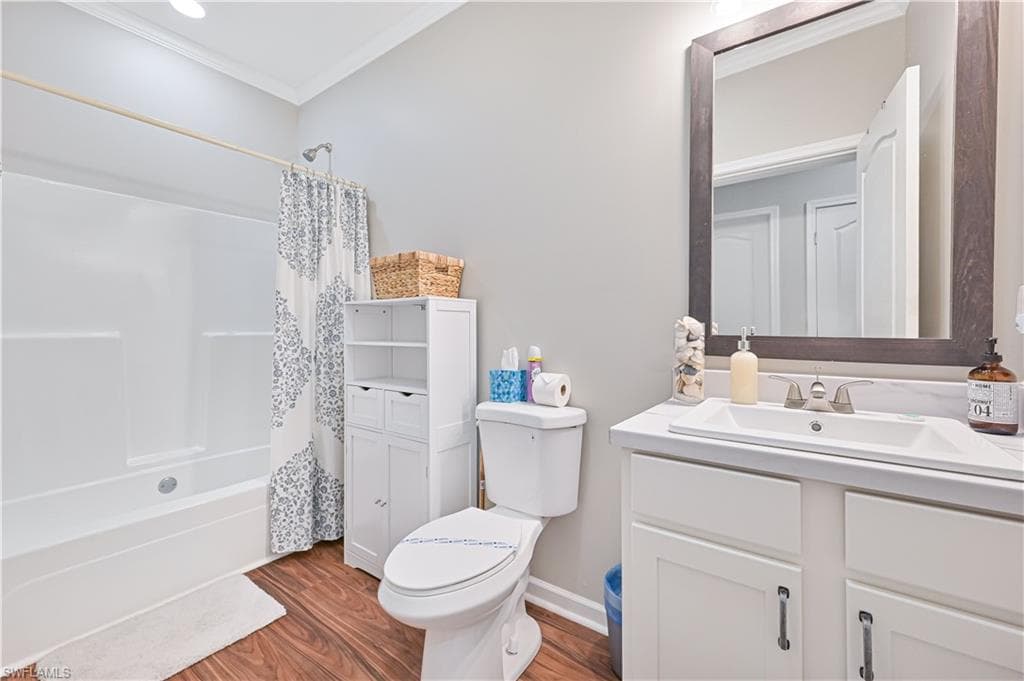 Full bathroom with vanity, shower / bath combo, crown molding, and wood finished floors