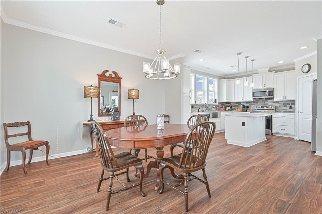 Dining room featuring a chandelier, ornamental molding, and dark wood-type flooring