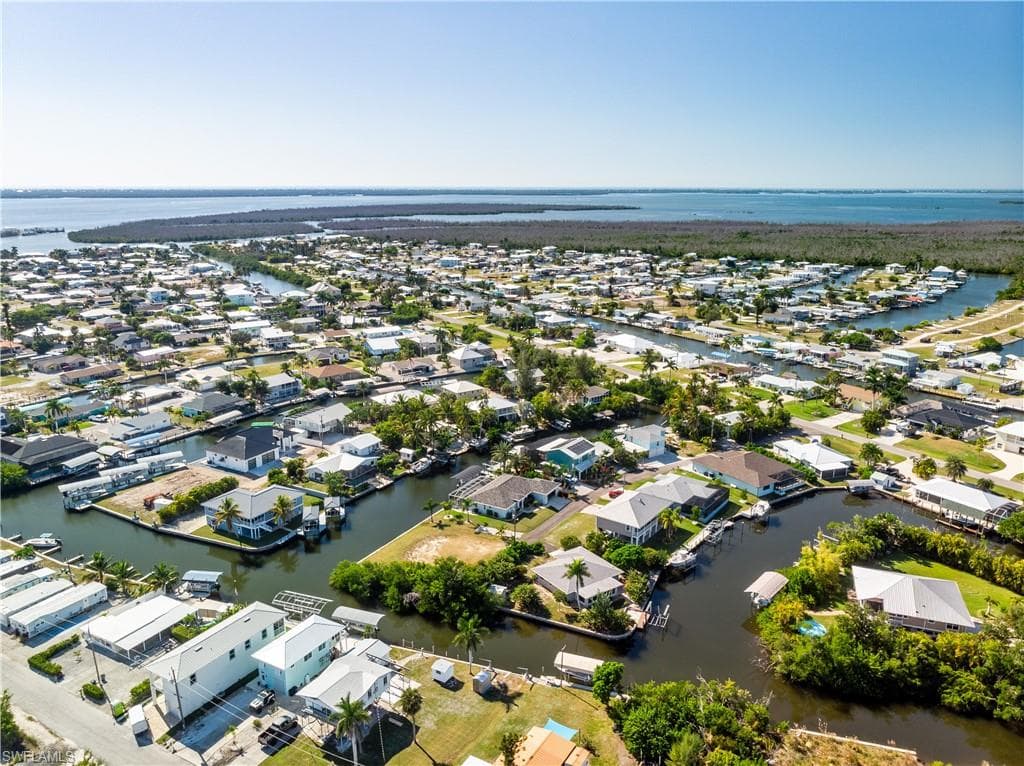 Aerial view of property and surrounding area with a nearby body of water and nearby suburban area