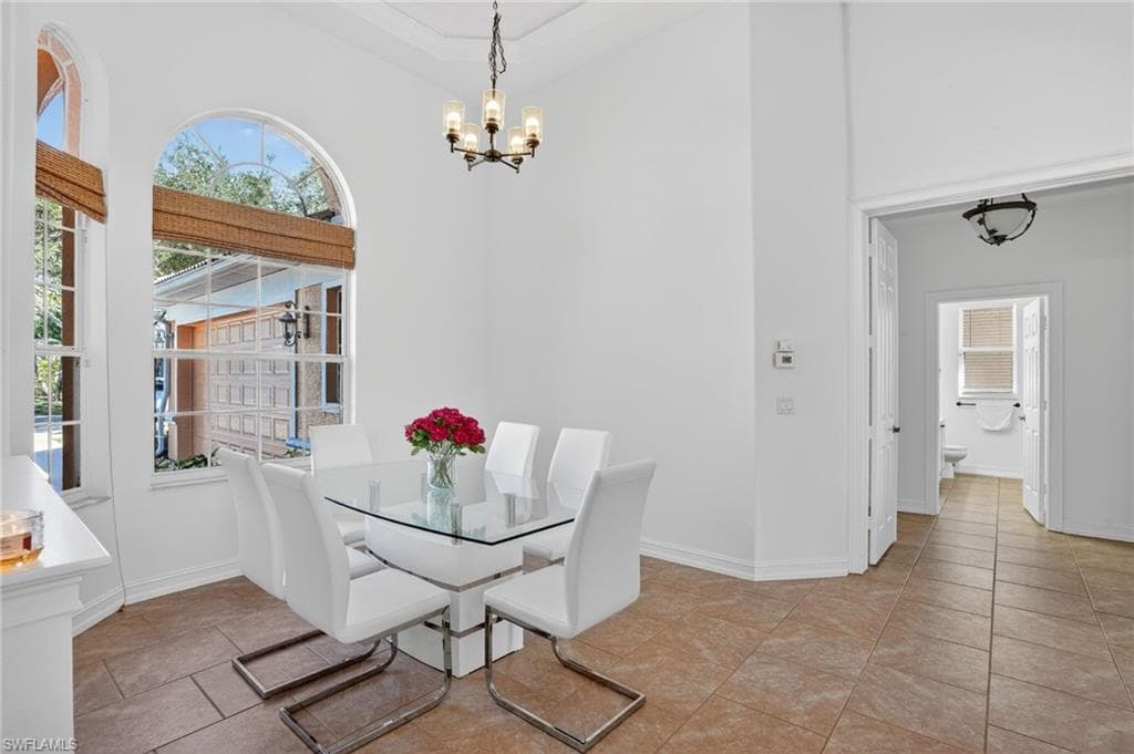 Dining space with light tile patterned flooring, a chandelier, and a high ceiling