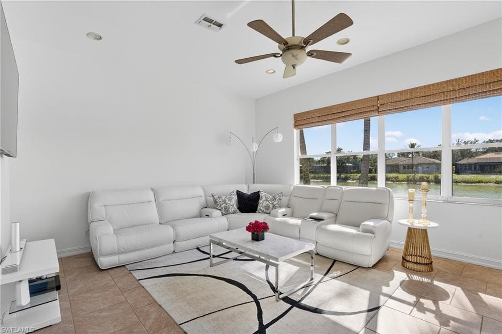 Living area with a water view, a ceiling fan, light tile patterned floors, and recessed lighting