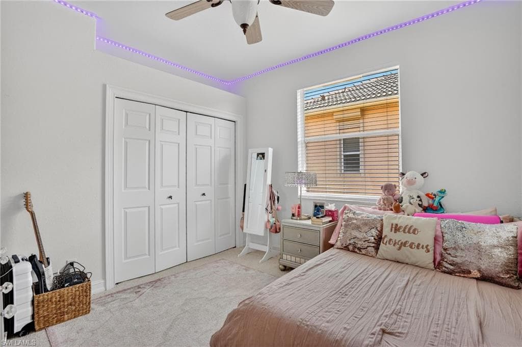 Bedroom featuring light colored carpet, a ceiling fan, and a closet