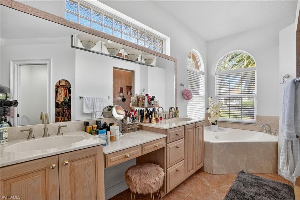 Full bathroom featuring a garden tub, double vanity, healthy amount of natural light, and light tile patterned flooring