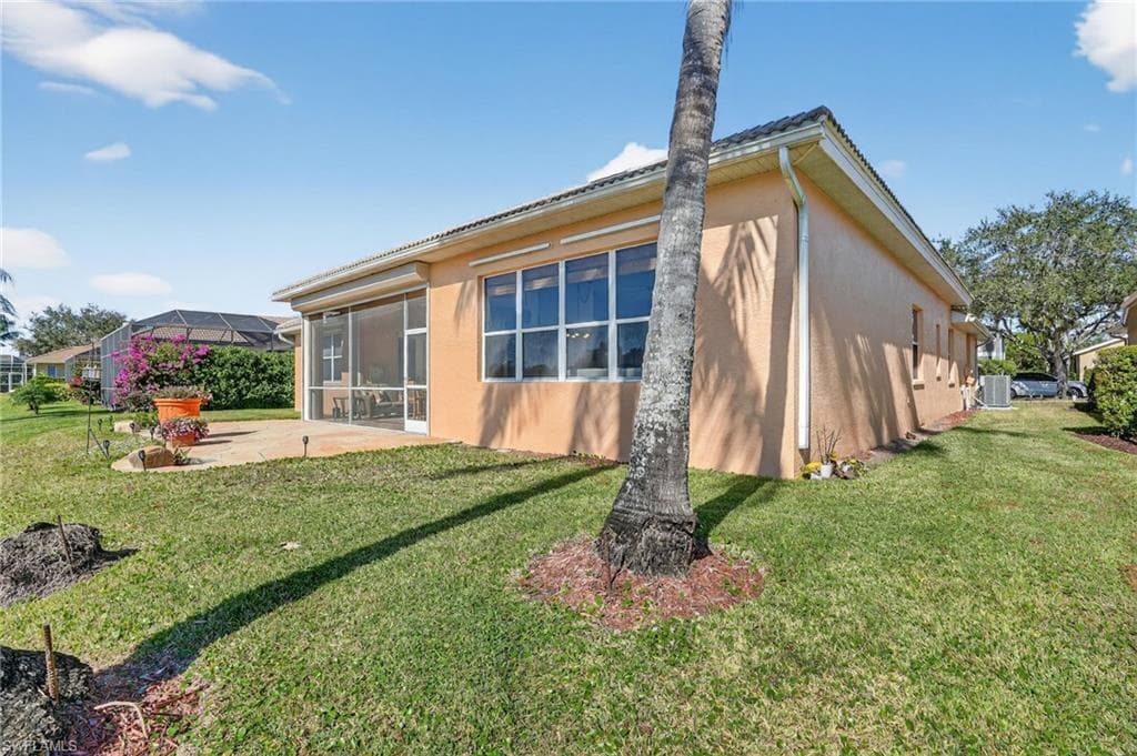 View of property exterior with stucco siding, a patio, and a lawn