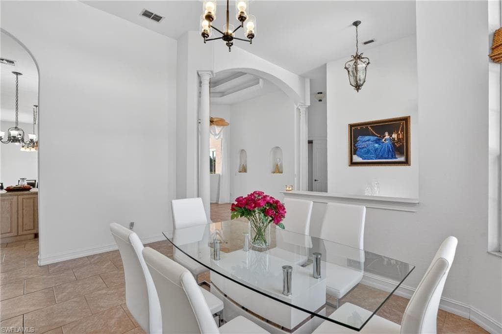 Dining space with a chandelier, arched walkways, and light tile patterned floors