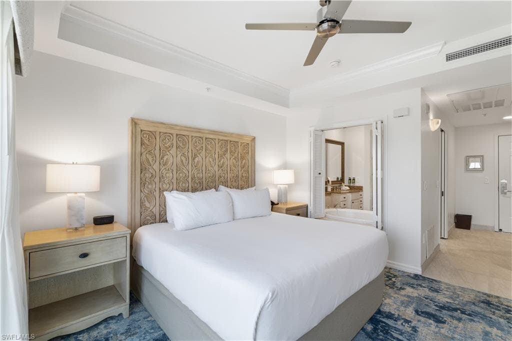 Bedroom with a tray ceiling, a ceiling fan, ornamental molding, and ensuite bathroom