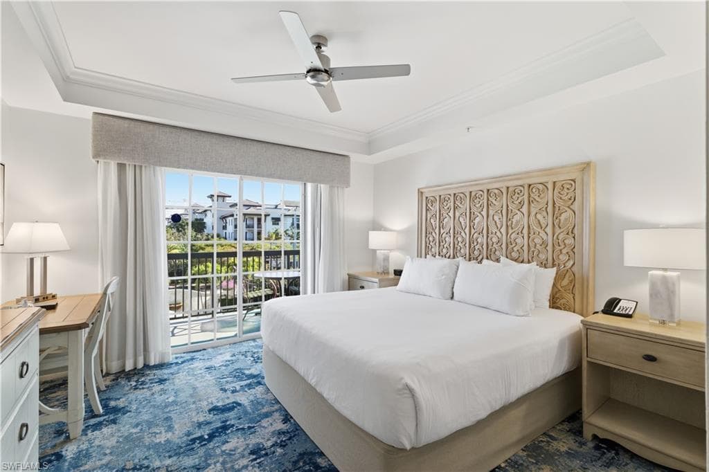 Bedroom featuring a tray ceiling, access to exterior, ceiling fan, and ornamental molding