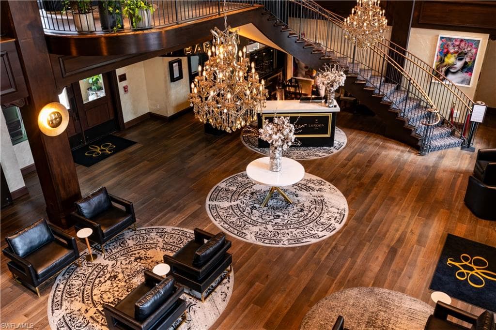 Living room with a chandelier, dark wood-style floors, stairway, and a towering ceiling