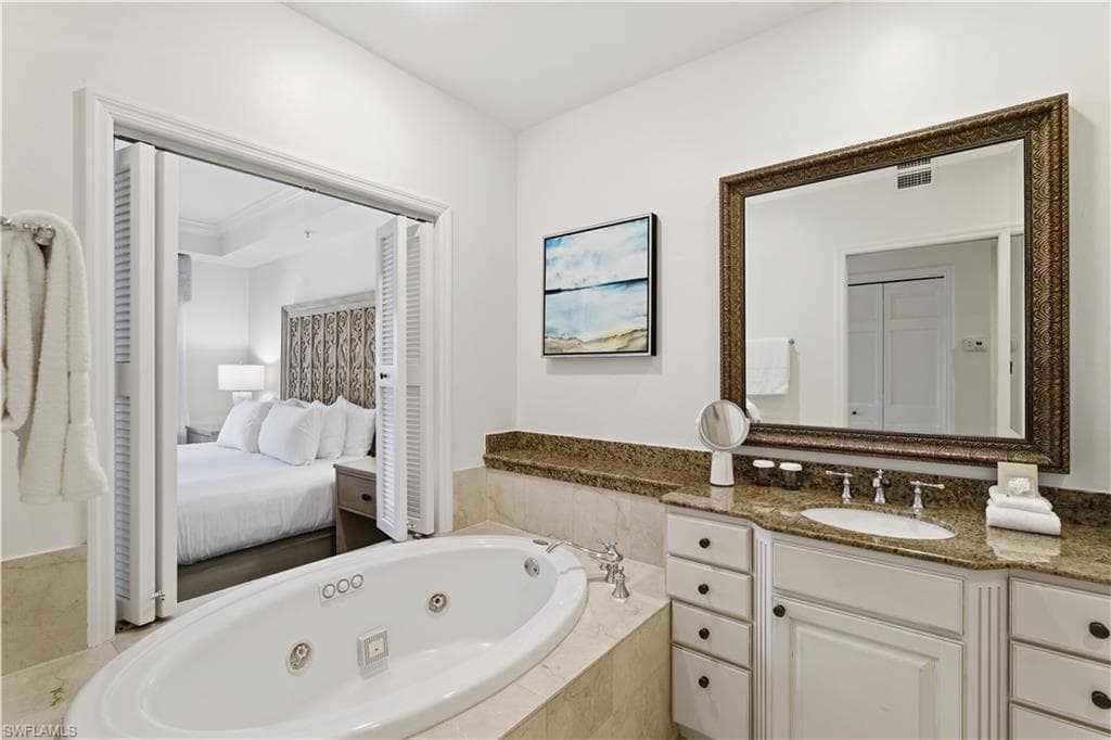 Ensuite bathroom with a whirlpool tub, vanity, and a closet
