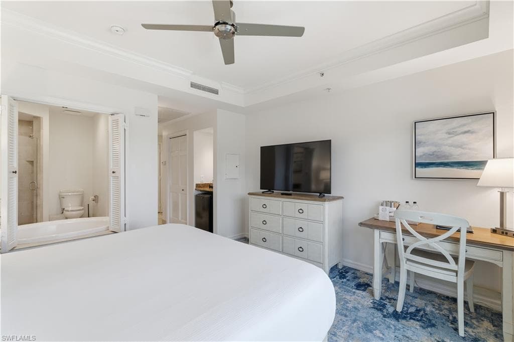Bedroom with ensuite bath, crown molding, a ceiling fan, and an office area