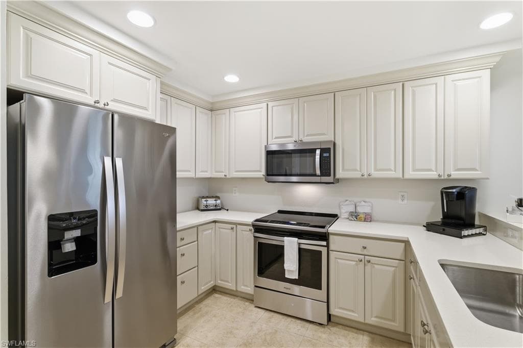 Kitchen with stainless steel appliances, recessed lighting, light tile patterned floors, and white cabinets