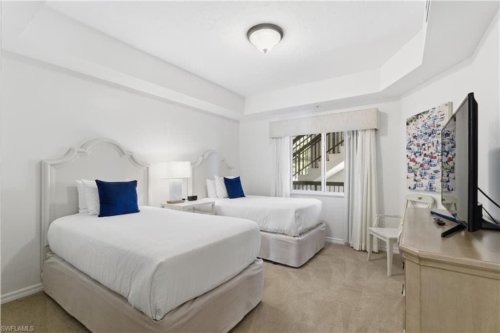 Bedroom with light carpet and a tray ceiling