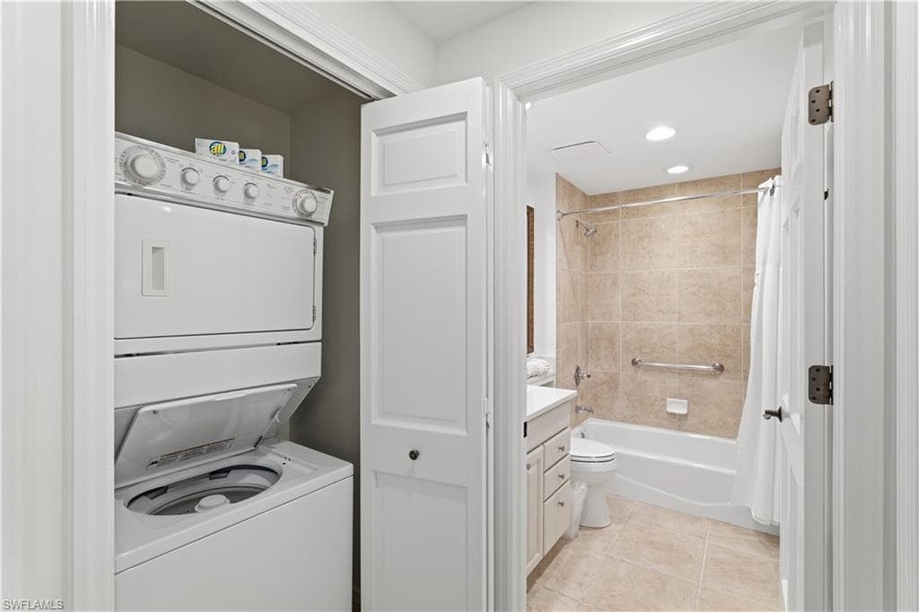 Laundry room featuring stacked washer and clothes dryer and light tile patterned floors