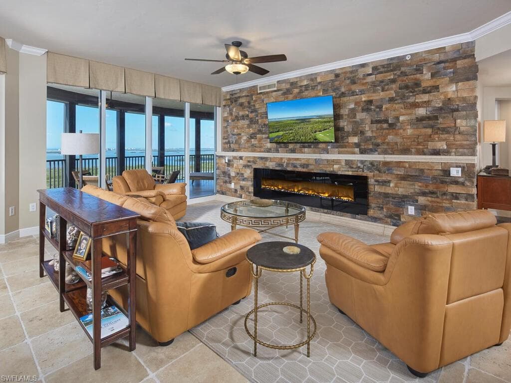 Living area featuring a fireplace, crown molding, and a ceiling fan