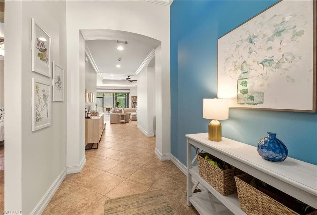 Corridor featuring crown molding, light tile patterned floors, arched walkways, and recessed lighting
