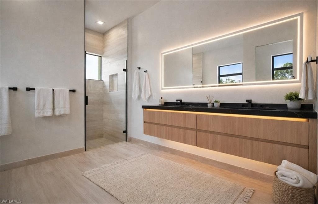 Bathroom featuring double vanity, light wood-style flooring, and a tile shower (Rendered photo)