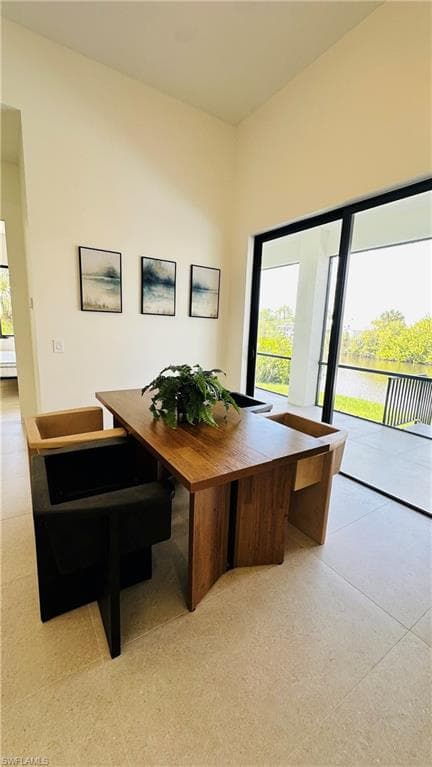 Open-concept room featuring high ceilings, light-toned tile flooring, and a full wall of sliding glass doors