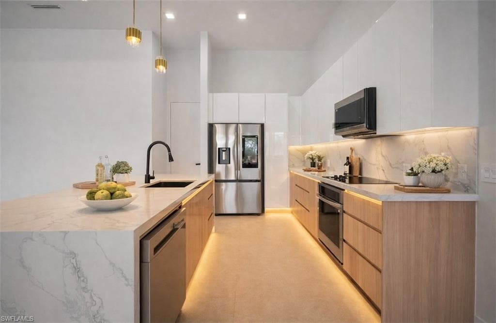 Kitchen with modern cabinets, pendant lighting, stainless steel appliances, light stone counters, and white cabinetry (Rendered photo)