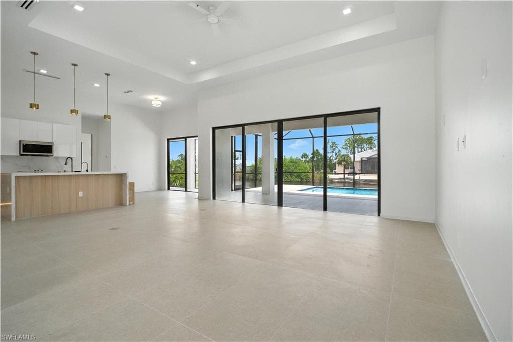 Unfurnished living room with recessed lighting, a raised ceiling, a high ceiling, and a ceiling fan