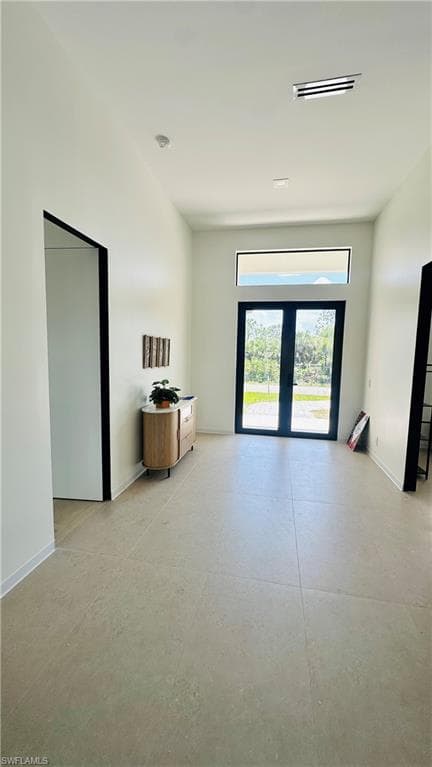 Entryway featuring large format tile flooring, high ceilings, recessed lighting, and a transom window above double glass doors