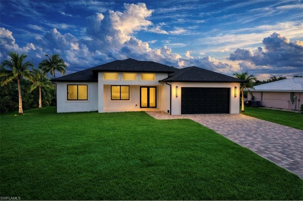 Prairie-style house featuring a yard, stucco siding, decorative driveway, and an attached garage (Rendered photo)