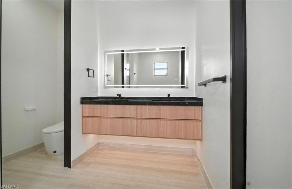 Full bath with double vanity and light wood-style floors