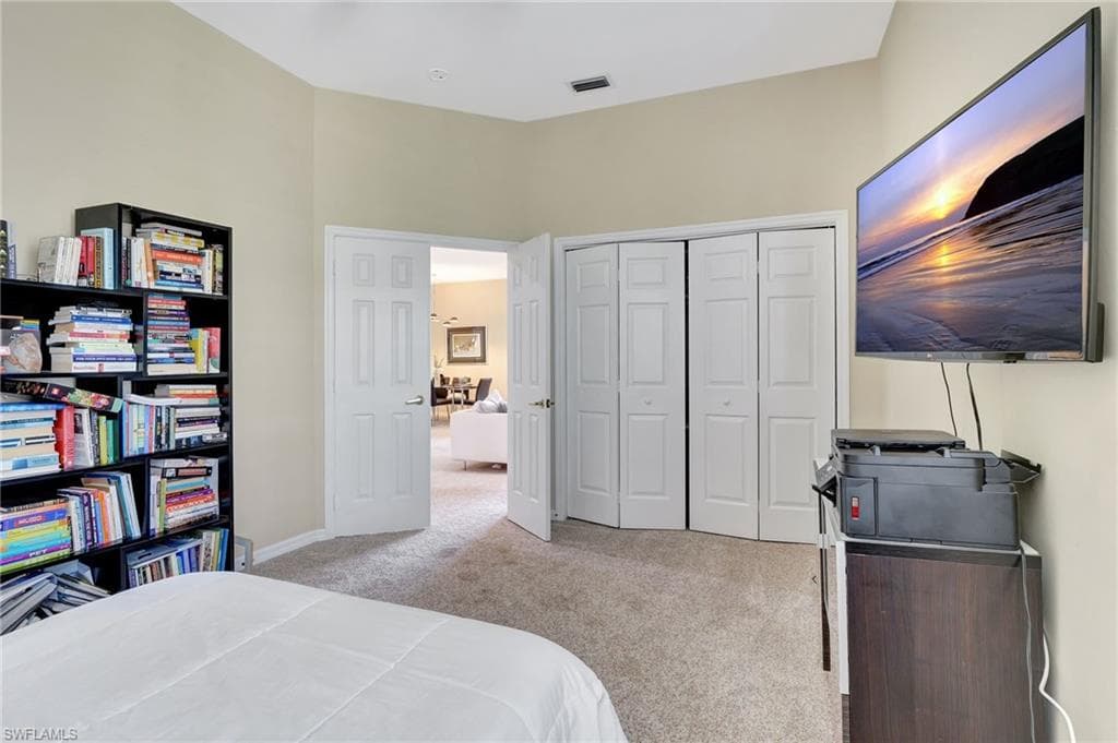 Carpeted bedroom with baseboards, visible vents, and a closet