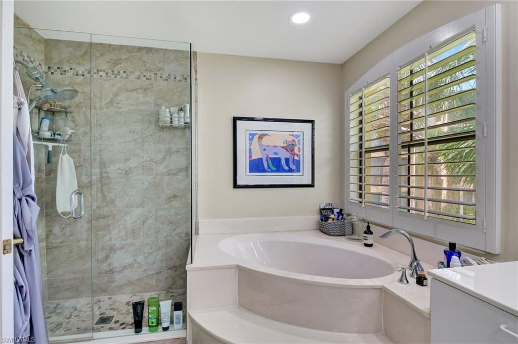 Full bathroom featuring recessed lighting, a stall shower, a bath, and vanity