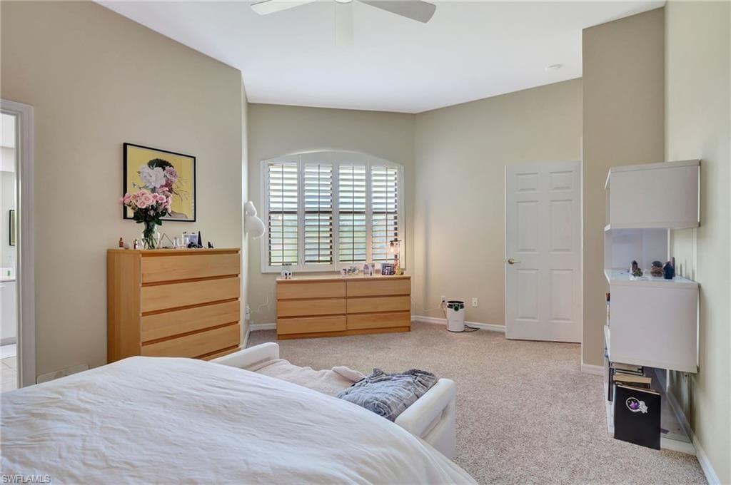 Carpeted bedroom featuring a ceiling fan and baseboards