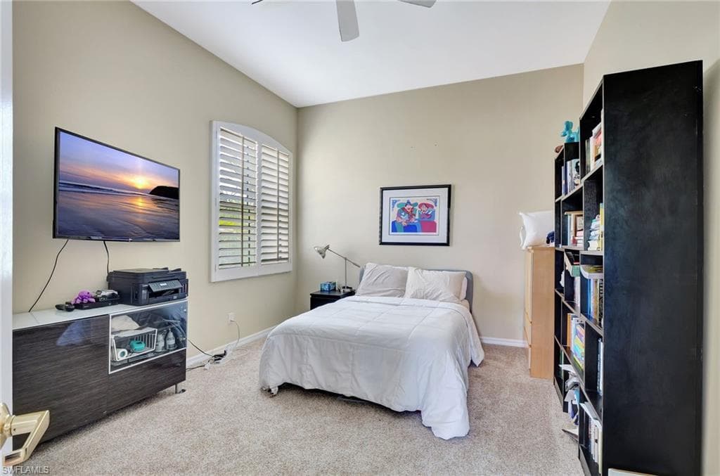 Bedroom featuring ceiling fan, baseboards, and light carpet