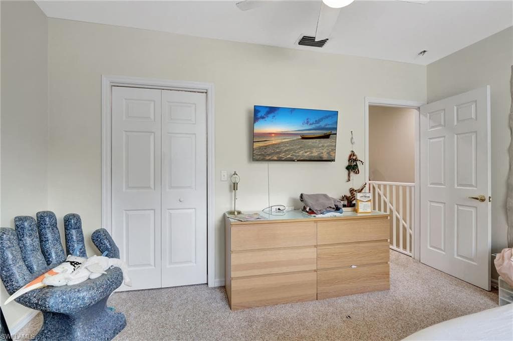Bedroom with visible vents, a closet, a ceiling fan, and light carpet