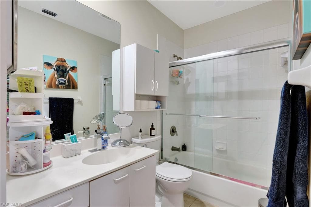 Bathroom with vanity, toilet, visible vents, enclosed tub / shower combo, and tile patterned flooring