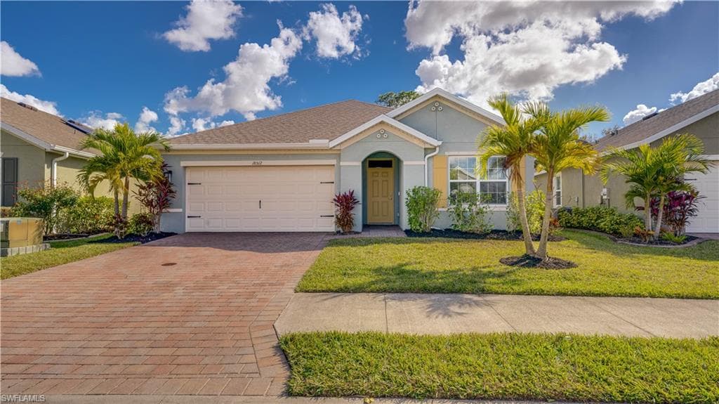 Ranch-style house with stucco siding, decorative driveway, a front lawn, and a garage
