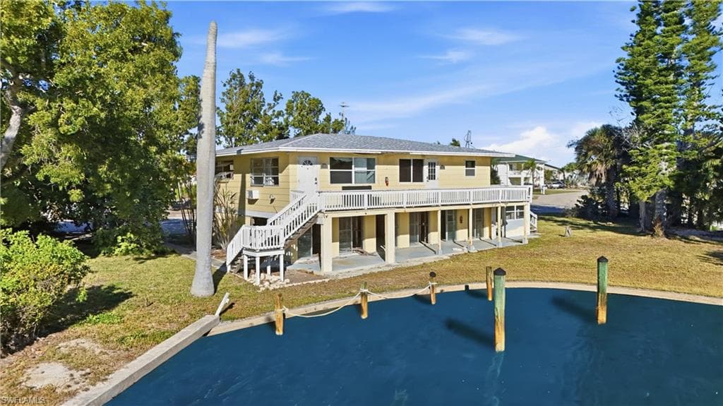 Back of property with a patio area, a yard, stairs, and a deck with water view - Virtually Edited Image