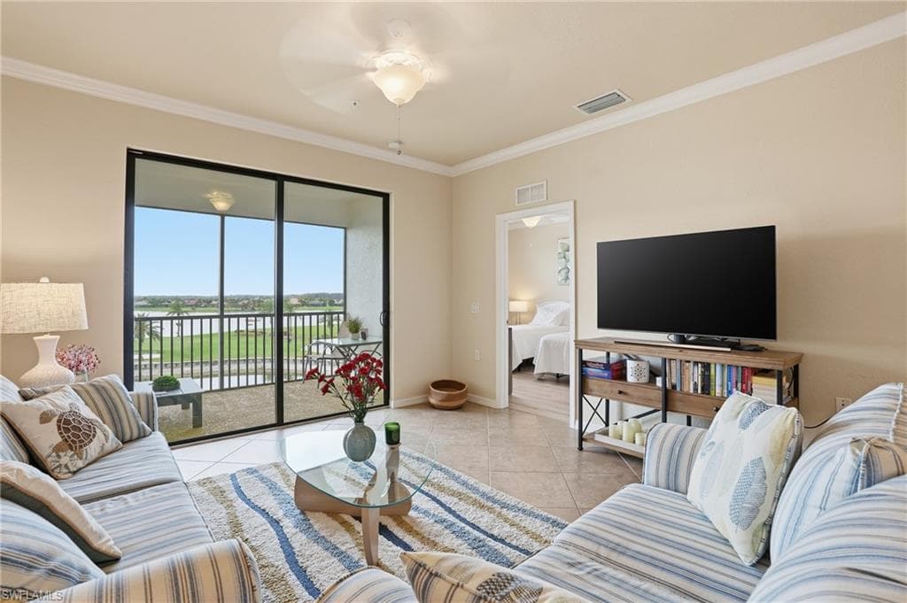 Living area featuring light tile patterned flooring, crown molding, and a ceiling fan