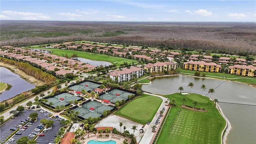 Aerial view of property and surrounding area featuring a golf club and a large body of water