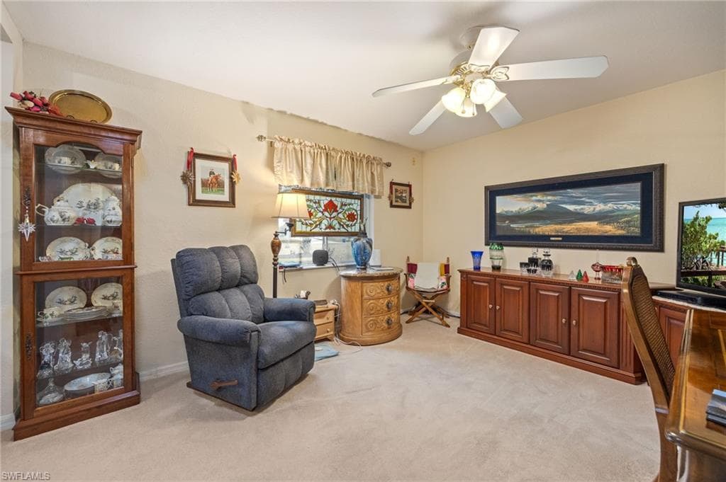 Sitting room with light carpet and a ceiling fan