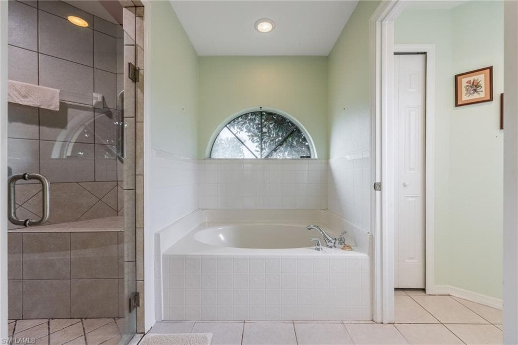 Bathroom with a garden tub, a shower stall, and light tile patterned floors