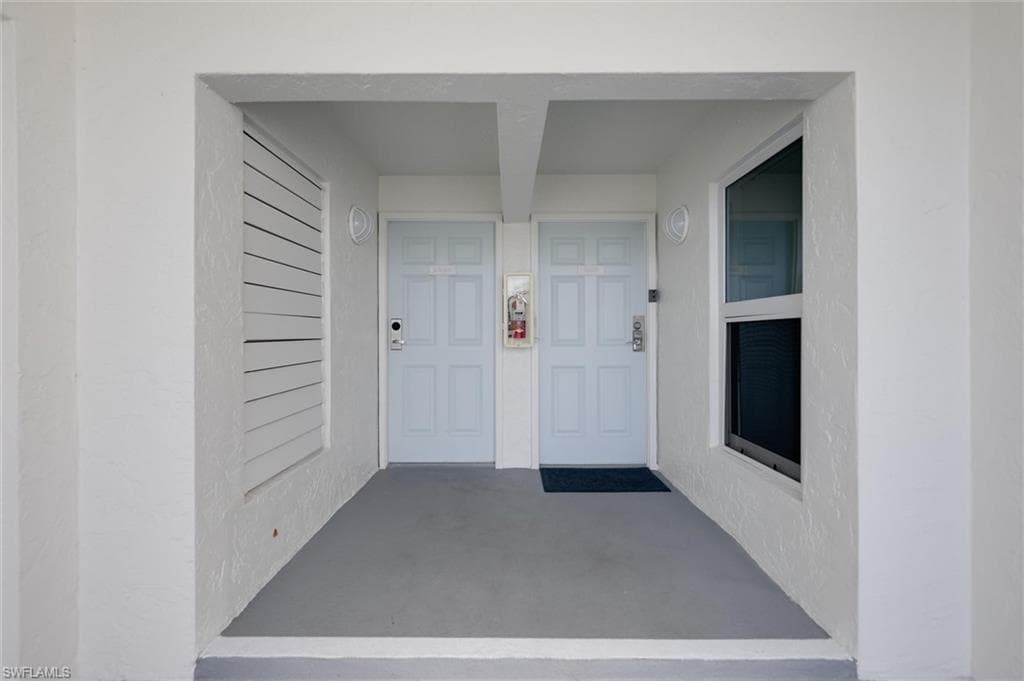 Entrance to property with covered porch and stucco siding
