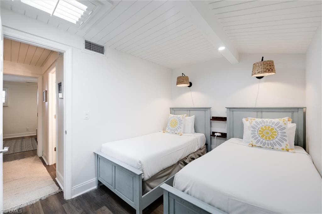 Bedroom with dark wood-type flooring and a wooden ceiling with exposed beams