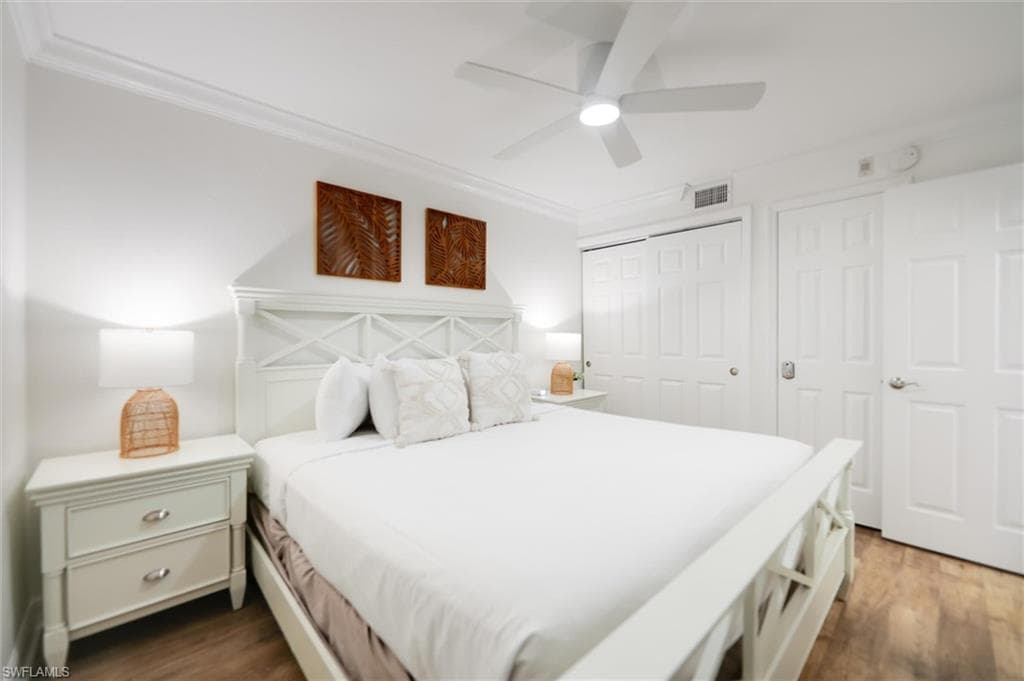 Bedroom featuring ornamental molding, a closet, dark wood-style floors, and a ceiling fan
