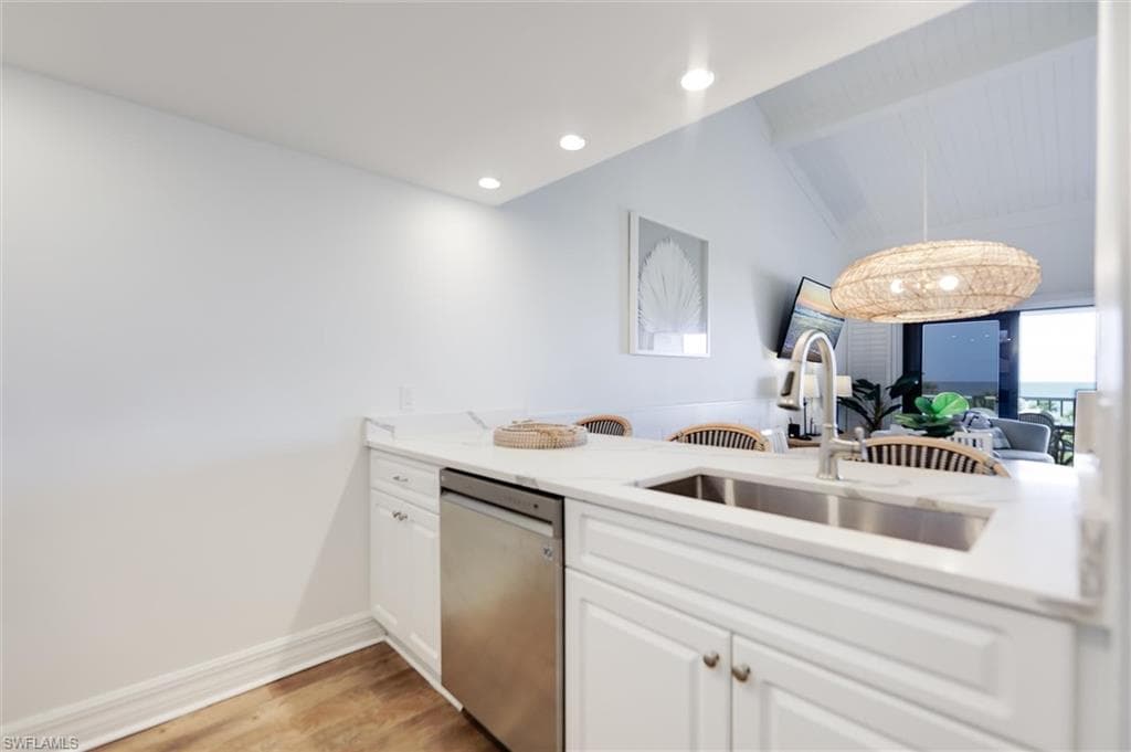 Kitchen featuring white cabinets, stainless steel dishwasher, light wood finished floors, recessed lighting, and light stone counters