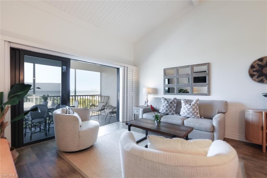 Living room featuring wood finished floors, high vaulted ceiling, a water view, and beamed ceiling