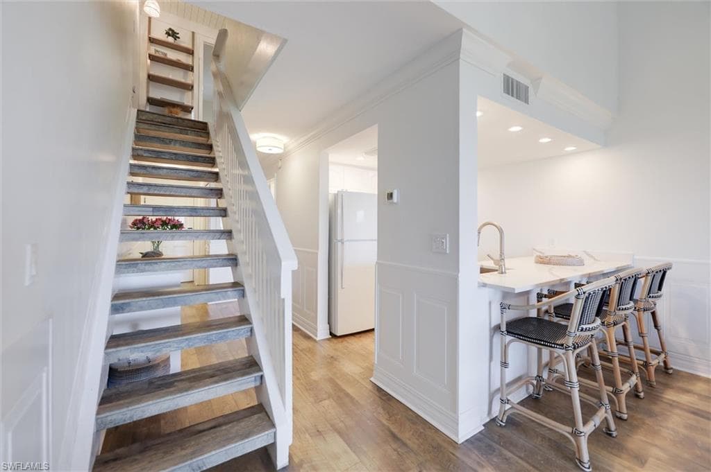 Stairs featuring wood finished floors and a decorative wall
